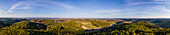 Aerial drone panoramic view of the wooded countryside under an almost clear sky on the border with Styria and Burgenland, Austria.