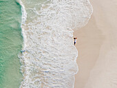 Aerial view of woman standing on beach in front of waves, Cape Town, South Africa.