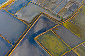Aerial view of the patterns and colors of salt evaporation ponds during sunrise time in Aveiro, Portugal