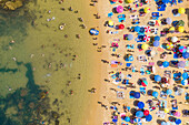 Aerial view above of people enjoying the summer at Praia do Camilo, Portugal.