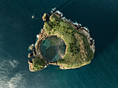 Aerial view of remote island with lush greenery and rocky cliffs, crystal clear blue water, Ilheu de Vila Franca de Campo, Azores, Portugal.