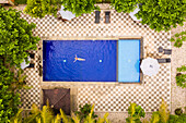 Aerial view of attractive girl floating over water at resort, Bali, Indonesia.
