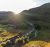 Luftaufnahme des Glenfiddich-Viadukts mit üppig grünem Tal und kurvenreicher Eisenbahn, Glenfinnan, Schottland.