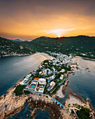 Aerial view of Shek O, a small settlement with beaches at sunset along the bay on Hong Kong island, China.