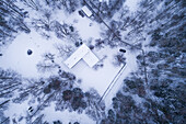 Aerial view of a house in the middle of the pine forest with snow Suurupi, Harju County, Estonia