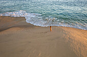 Aerial view of a person walking on the beach at sunset at Playa de los Amantes, Cabo San Lucas, Baja California, Mexico.