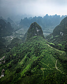 Aerial view of lush karst mountains and serene valley with vibrant greenery, Guilin, China.