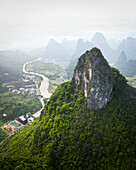 Aerial view of majestic karst mountains and a tranquil river in a lush valley, Guilin, China.