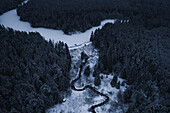 Snowy evening aerial view of a car stopping on a dam next to a river and lake in Estonia.