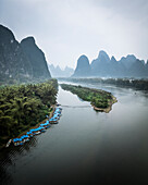 Aerial view of serene river winding through majestic karst mountains with lush greenery, Guilin, China.