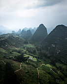 Aerial view of majestic karst mountains and a tranquil valley with a winding path, Guilin, China.