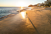 Aerial view of a person walking on the beach at sunset at Playa de los Amantes, Cabo San Lucas, Baja California, Mexico.