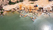Aerial view of boats on green water near sandy shore with sand mining activity, Eleme, Nigeria.