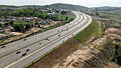 Aerial view of scenic highway with cars amidst lush greenery and rolling hills, Abuja, Nigeria.
