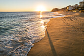 Aerial view of a person walking on the beach at sunset at Playa de los Amantes, Cabo San Lucas, Baja California, Mexico.
