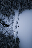 Snowy evening aerial view of a car stopping on a dam next to a river and lake in Estonia.