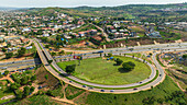 Aerial view of a beautiful urban landscape featuring roads, buildings, and greenery amidst hills, Abuja, Nigeria.