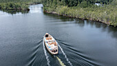 Aerial view of a serene river with a boat carrying food surrounded by lush forest and tranquil water, Akuku-Toru, Nigeria.
