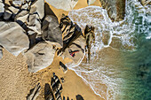 Aerial view of people relaxing on the rocks along the coast at Playa de los Amantes, Cabo San Lucas, Baja California, Mexico.
