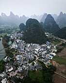 Aerial view of beautiful karst mountains and a quaint village by a river in a scenic valley, Guilin, China.
