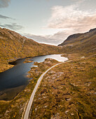 Aerial view of beautiful lake next to curvy mountain road in Norway