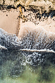 Aerial view of the baltic sea crashing on the black sand of the beach in Estonia.