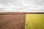 Aerial view of a man standing up at the separation between two different colored fields in Estonia.