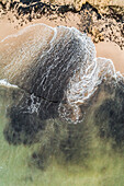 Aerial view of the baltic sea crashing on the black sand of the beach in Estonia.