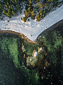 Aerial view of the snowy coast and green sea of Estonia.