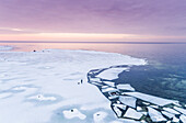 Aerial view of a man walking his dog on the frozen sea in Muraste at sunset, Estonia.