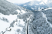 Aerial view of snowy mountains with frozen trees and cottages along a road, Morgins, Switzerland.