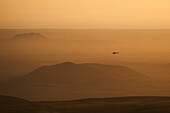 Aerial view of a helicopter flying low in the mist with a beautiful landscape in background at sunset, Grindavík, Southern Peninsula, Iceland.