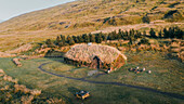 Aerial view of traditional turf houses amidst serene greenery and hills, Eiriksstadir, Iceland.