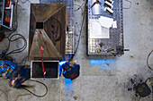 Chicago, Illinois - 17 April 2019: Aerial view of a man working alone in a warehouse sawing metal with a grinder