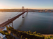 Panoramablick aus der Vogelperspektive auf die Autobahn am 25. April, Brücke über den Tejo mit der Innenstadt von Lissabon im Hintergrund, Lissabon, Portugal.