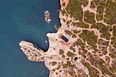Luftaufnahme von oben auf die wilde Küste in der Nähe von Praia da Marinha mit kleinen paradiesischen Stränden bei Sonnenaufgang, Lagoa, Algarve-Region, Portugal