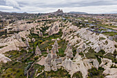 Aerial view of Goreme Valley and National Park with fairy chimney rock formation with Uchisar castle and town in background Cappadocia, Nevsehir, Turkey.