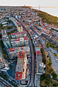 Aerial view of Cacilhas little township along the Tagus river at sunset with April 25th bridge and Cristo Rei statue in background, Almada, Portugal.