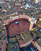 Luftaufnahme des Torre del Mangia mit der Stadtsilhouette bei Sonnenuntergang, einer berühmten Sehenswürdigkeit auf der Piazza del Campo, Siena, Toskana, Italien.