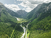 Aerial view of a road crossing the valley across Tre Cime Natural park (Drei Zinnen) with Monte Cristallo in background on the Dolomites area, Trentino, South Tyrol, Italy.