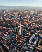 Aerial view of the Mole Antonelliana tower, a landmark building in Turin downtown at sunset with the Alps mountains range in background, Turin, Piedmont, Italy.
