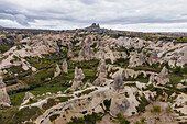 Aerial view of Goreme Valley and National Park with fairy chimney rock formation with Uchisar castle and town in background Cappadocia, Nevsehir, Turkey.