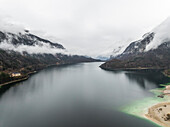 Luftaufnahme des Molveno-Sees mit malerischen Dolomiten im nebligen Norditalien.