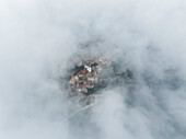 Luftaufnahme von Trentinara, einer kleinen Stadt auf einem Berggipfel mit niedrigen Wolken und dichtem Nebel Salerno, Kampanien, Italien.