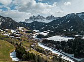 Aerial view of Val di Funes with snowy Dolomites in the background, South Tyrol, Italy.