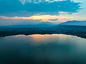 Luftaufnahme des ruhigen Viverone-Sees, in dem sich der heitere Himmel und die majestätischen Berge bei Sonnenuntergang spiegeln, Viverone, Italien.