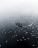 Aerial view of boats on the serene Yamuna river with birds and low clouds, Sadar Bazar, New Delhi, India.