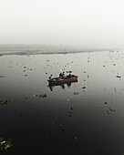 Aerial view of boats and people along the Yamuna river with birds flying overhead, Sadar Bazar, New Delhi, India.
