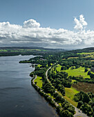 Aerial view of loch lomond surrounded by lush greenery and a winding road, trossachs national park, scotland, united kingdom.