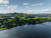 Aerial view of tranquil Loch Lomond surrounded by lush hills and serene forest, Trossachs National Park, United Kingdom.